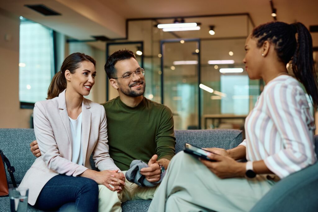 Happy couple having counseling with African American financial advisor in the office.